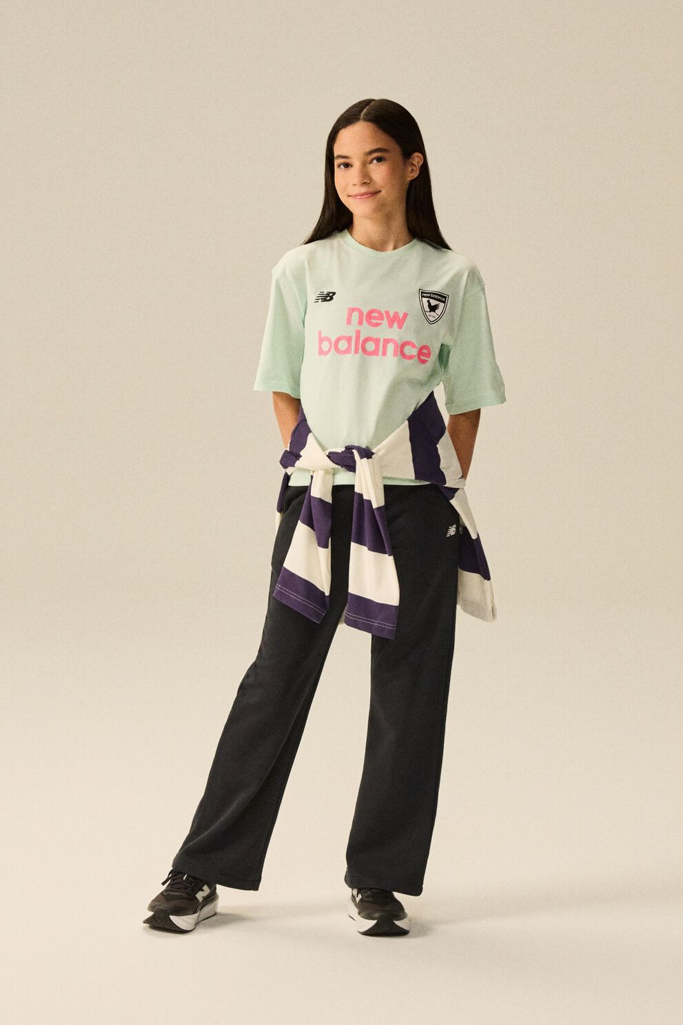 Young kid standing in front of a bike wearing blue jeans and a pink shirt. 