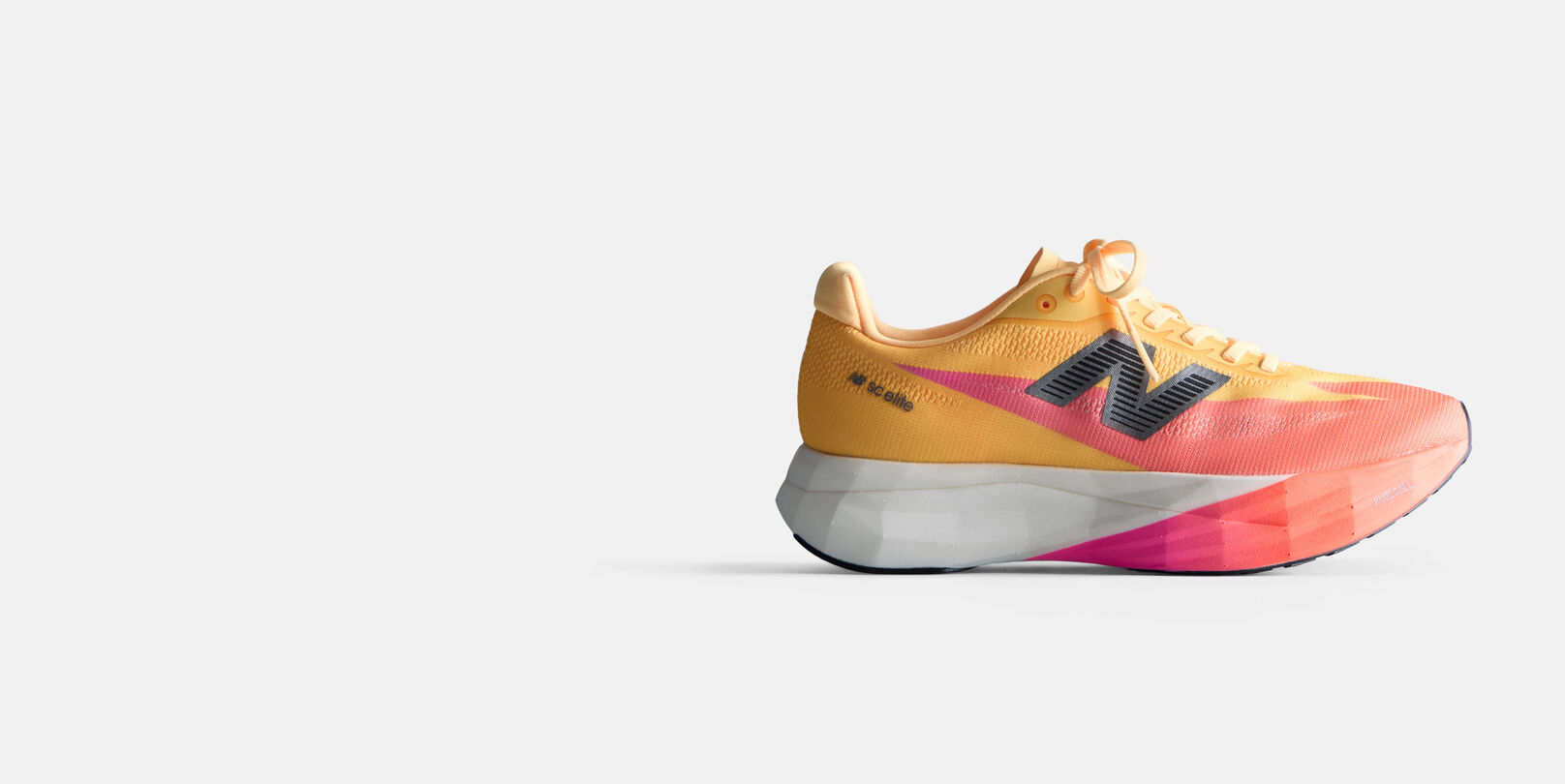 Orange and peach running shoe with a white midsole and black New Balance logo on a white background. 