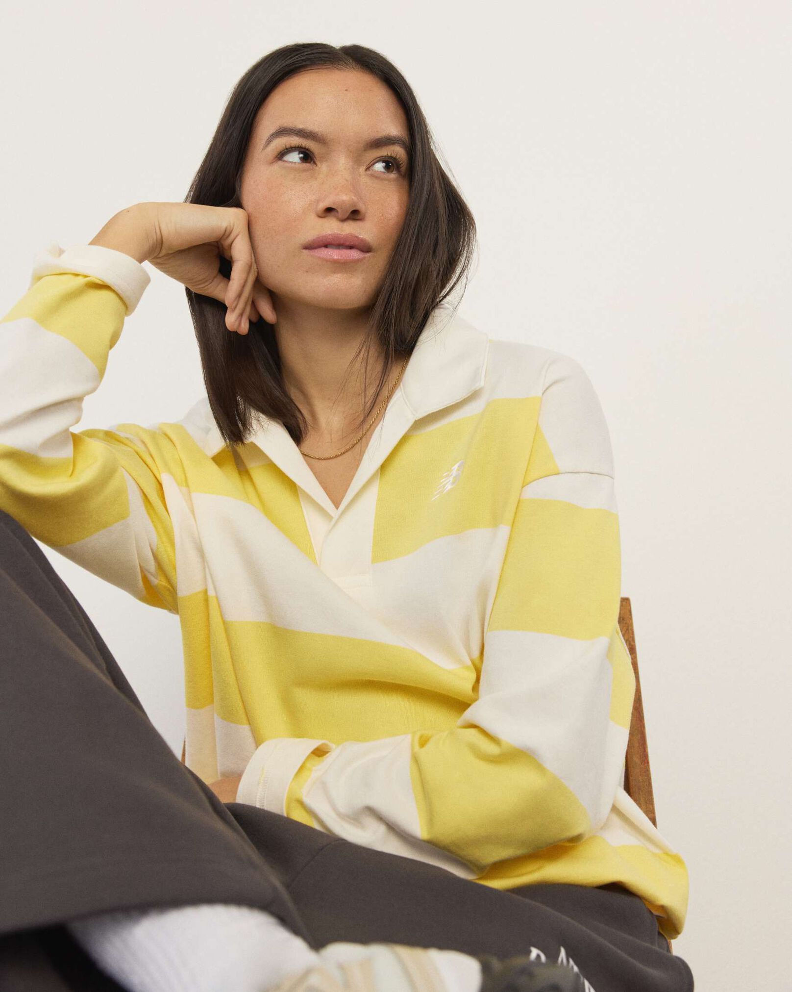 A woman wearing New Balance standing in front a white wall.